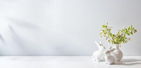 Spring flowers in a vase and easter bunny on a white table. Easter background with copy space