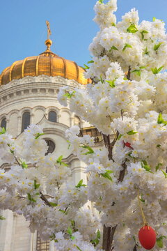 Easter egg among white flowers on the background of the church dome