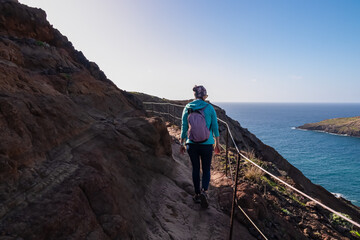 Hiker woman on idyllic hiking trail along rocky rugged cliffs at Ponta de Sao Lourenco peninsula,...