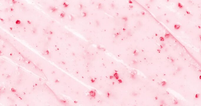 Close up video on strawberry ice cream texture. Top view. Camera sliding on pink fruit ice cream background with small pieces of berries.