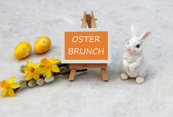 Der Text Osterbrunch auf einer Tafel mit Osterdekoration und Blumen.	