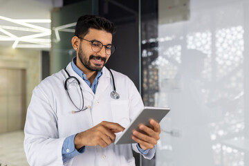 Confident young male healthcare professional working with a tablet in a bright medical office setting, embodying the blend of technology and care.