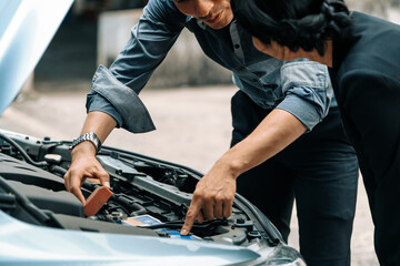 Man help woman fix the car problem. He pop up the car hood to repair the damaged part. uds - obrazy, fototapety, plakaty