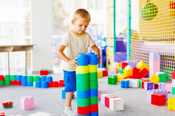 Child playing with colorful building blocks in a playroom setting