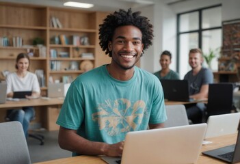 Happy young man with laptop in modern office. Bright space with team collaboration in the background.
