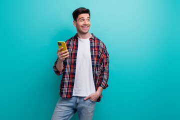 Photo of funny dreamy guy wear checkered shirt typing modern gadget looking empty space isolated blue teal color background - obrazy, fototapety, plakaty