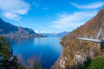Driving car along shores of Lake Como in Northern Italy, spring sunny days, views of alpine mountains, water and villages - obrazy, fototapety, plakaty