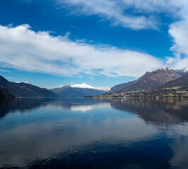 Driving car along shores of Lake Como in Northern Italy, spring sunny days, views of alpine mountains, water and villages