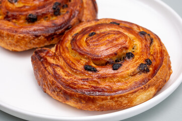 Breakfast in bakery with fresh baked coffee buns sweet pastry with raisins, morning food close up