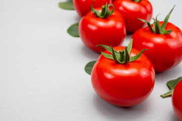Food ornament, Red ripe tasty Dutch tomatoes and spinach leaves, vegetables background top view close up copy space