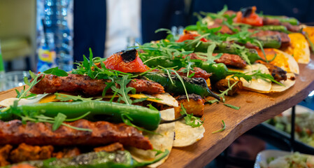 Wooden plate with Turkish mixed grill meat, chicken wings, lamb, beef shashlik, kebab, peppers from charcoal grill in restaurant