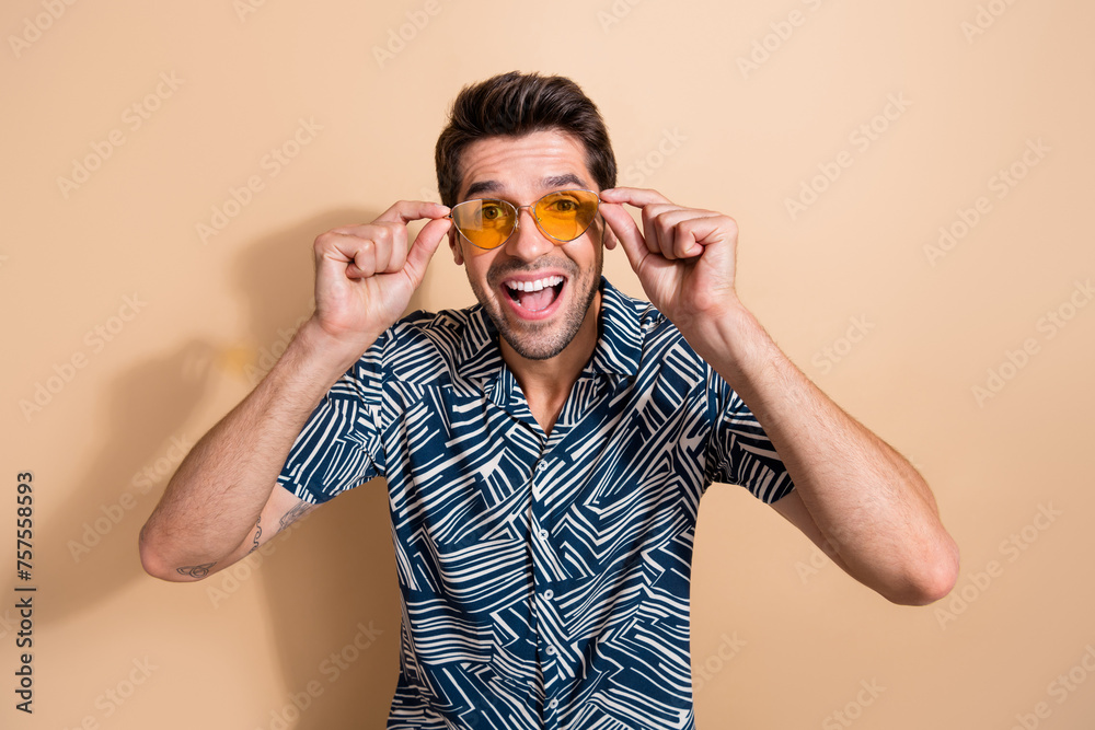 Sticker Photo of cheerful nice cool man dressed fashionable summer clothes specs enjoying summer rest resort isolated on beige color background