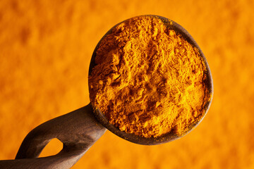 Orange turmeric root powder on a spoon