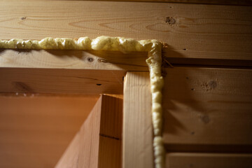 Repair in a wooden house. Slots in the door. Polyurethane foam on a board.