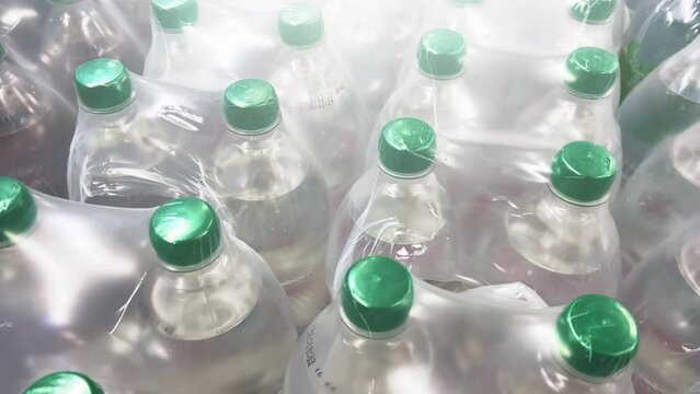 Rows of mineral or table water in two-liter bottles packed in 6 bottles stand in warehouse. Close up shot
