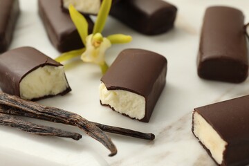 Glazed curd cheese bars, vanilla pods and flower on white board, closeup