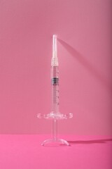 Cosmetology. One medical syringe on pink background