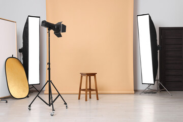 Beige photo background, stool and professional lighting equipment in studio