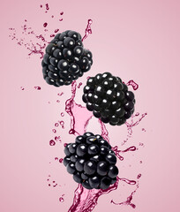 Fresh blackberries and juice in air on pink background