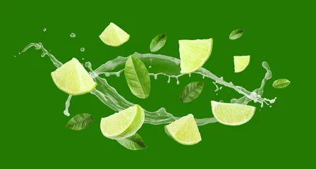 Rolgordijnen Pieces of lime, leaves and splashes of juice flying on green background, banner design © New Africa