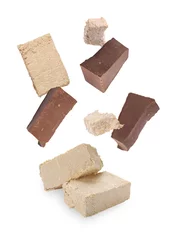Rolgordijnen Pieces of tasty halva and chocolate falling on white background © New Africa