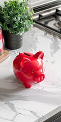 A red piggy bank contrasting the modernity of the kitchen with a touch of nostalgia and simplicity. Red piggy bank in a white kitchen about the importance of financial savings.