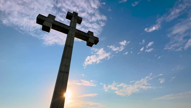 Low angle: huge stone cross monument on the mountain over Gonio town near Batumi, Georgia at sunset - sun lens flares. Christianity, Orthodoxy, hope, religion, spiritual and freedom concept