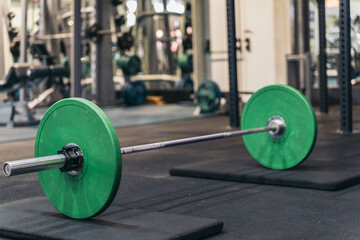 Weightlifting bar and discs on rubber support, no people present.
