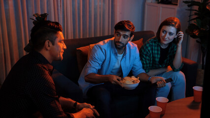 Top view of caucasian father and relaxed mother watching movie while eating snack with friend....