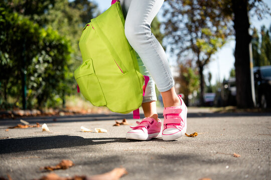 Cropped photo of cute little girl legs dressed pink sneakers holding backpack walking enjoy good weather outdoors urban city park