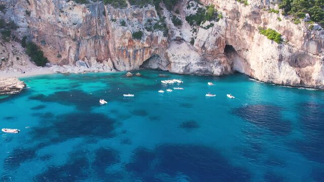 Aerial drone view on white sand Cala Baunei in Orosei Gulf of Sardegna. Warm turquoise sea and small beach surrounded with green mountains on the Sardinia island.