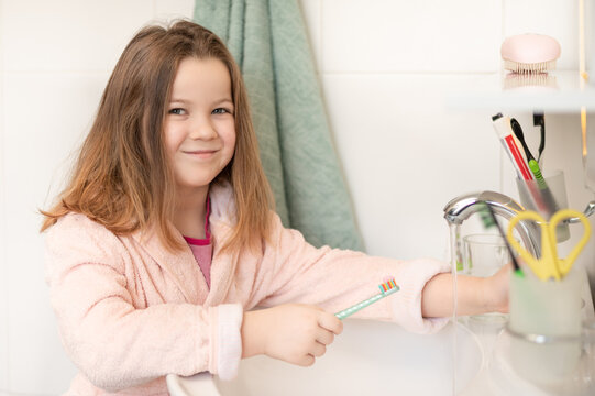 Happy 7 year old child brushes his teeth in the bathroom near the mirror with a toothbrush. High quality photo