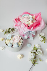 Festive Easter table in delicate colors: cake decorated with meringue, icing, flowers. Sweets in the form of flowers, apple blossoms, Easter eggs.