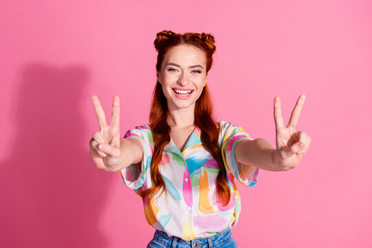 Portrait of positive adorable woman hands touch silky curl wear print shirt show you v-sign say hi isolated on pink color background