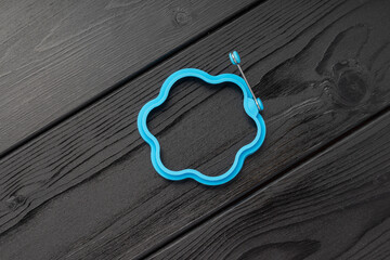 A blue silicone bracelet with a flower-like outline on a wooden surface