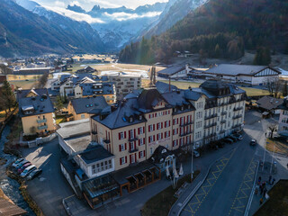 Fototapeta na wymiar Aerial view of Engelberg resort with the prominent HOTEL BELLEVUE and its redwhite facade. Nearby, clean streets and mountainstyle buildings nestle against a backdrop of majestic, snowcapped peaks.