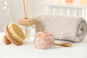 Fototapeta na wymiar Spa composition. Sea salt, brush, towel and reed air freshener on soft white surface