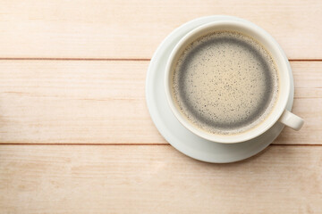 Cup of aromatic coffee on light wooden table, top view. Space for text