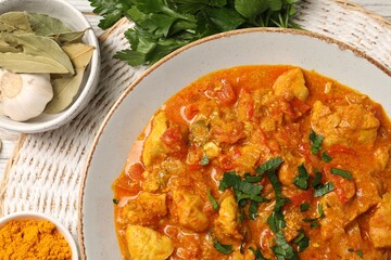 Delicious chicken curry and ingredients on table, top view