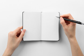 Woman writing in notebook on white background, top view