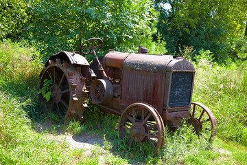 Old fashioned tractor resting in a green field on a summer day