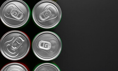 Energy drink in cans on black background, top view. Space for text