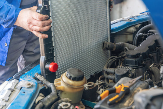 A man installs a new radiator in a car