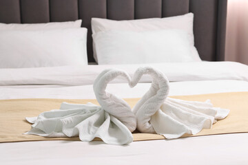 Fototapeta na wymiar Honeymoon. Swans made of towels on bed in room