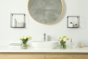 White sink between beautiful roses and toiletries in bathroom