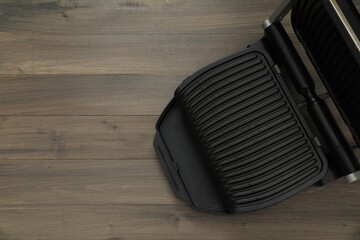 Electric grill on wooden table, top view. Space for text. Cooking appliance