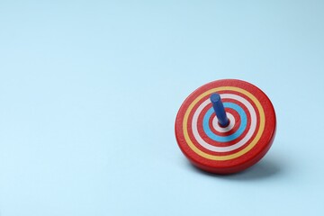 One colorful spinning top on light blue background, space for text