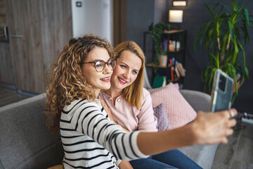 Two Women Sitting on a Couch Taking a Selfie