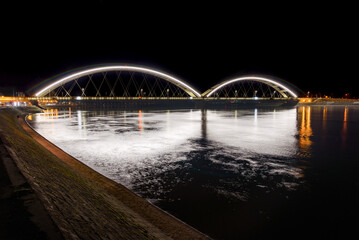 New illuminated Zezelj bridge over the Danube river in Novi Sad, Serbia with light and reflection in the water night 