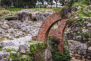 Arches in reamains of Roman Amphitheater in Neapolis archaeological park of Syracuse, Sicily Island in Italy
